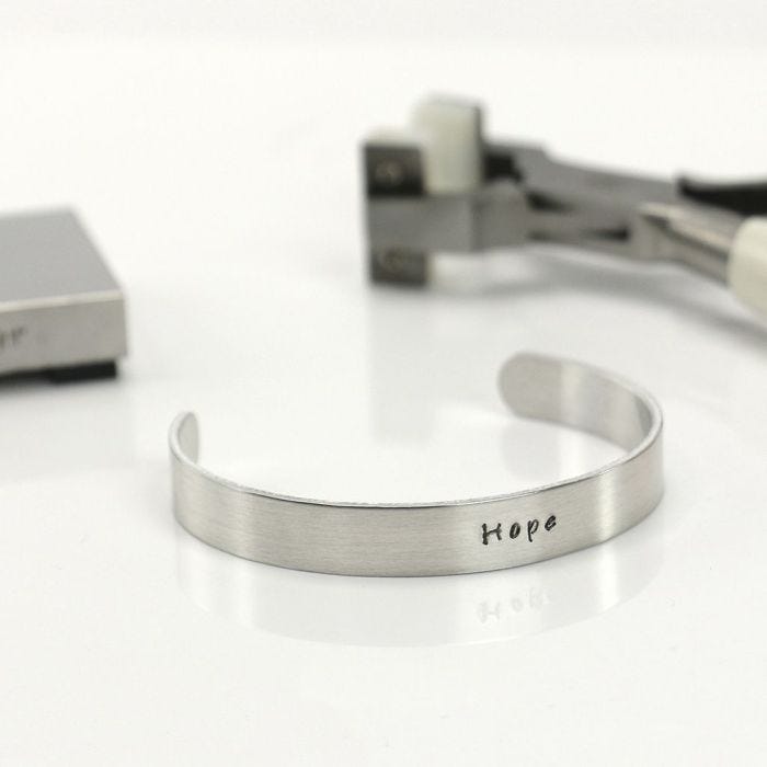 A Bracelet made from a Metal Band stamped with a Text