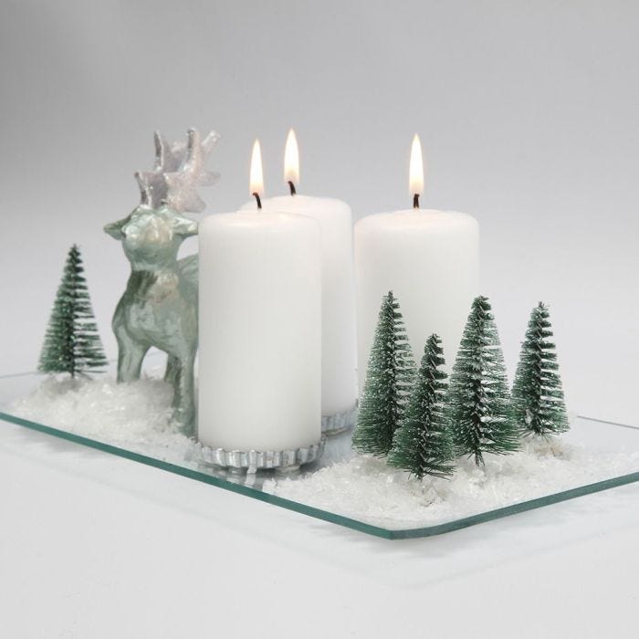 A Christmas Decoration with Candles, Reindeer, Trees and Snow on a Glass Dish