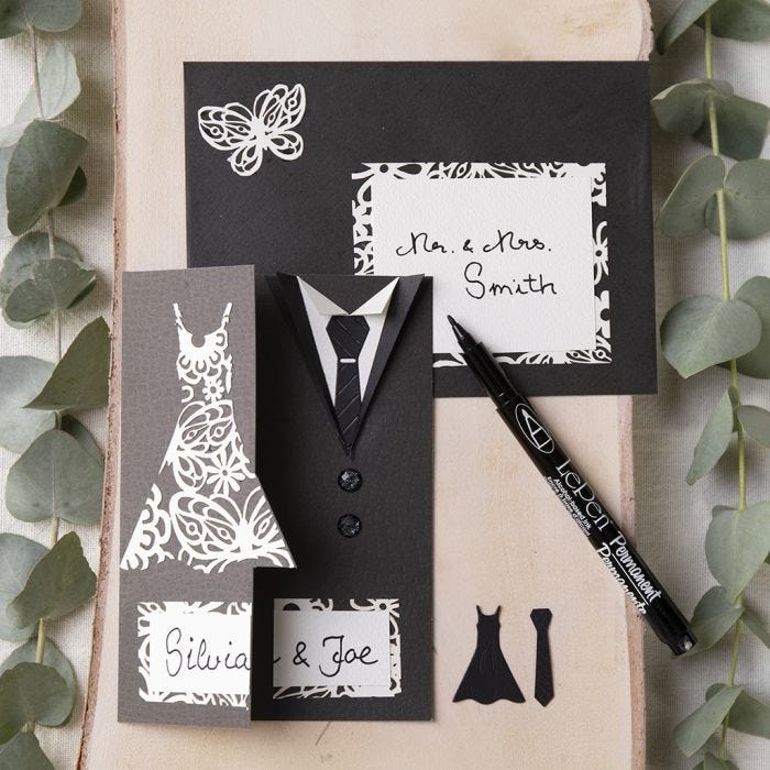 A wedding invitation decorated with a dress and a dinner jacket