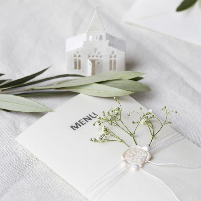 A menu card in off-white shades with a punched-out church and vellum paper