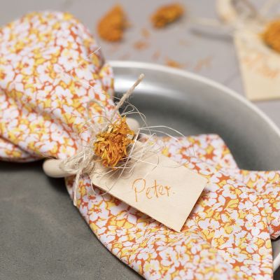 Serviettes en tissu patchwork et un anneau de serviette décoré de fleurs séchées.