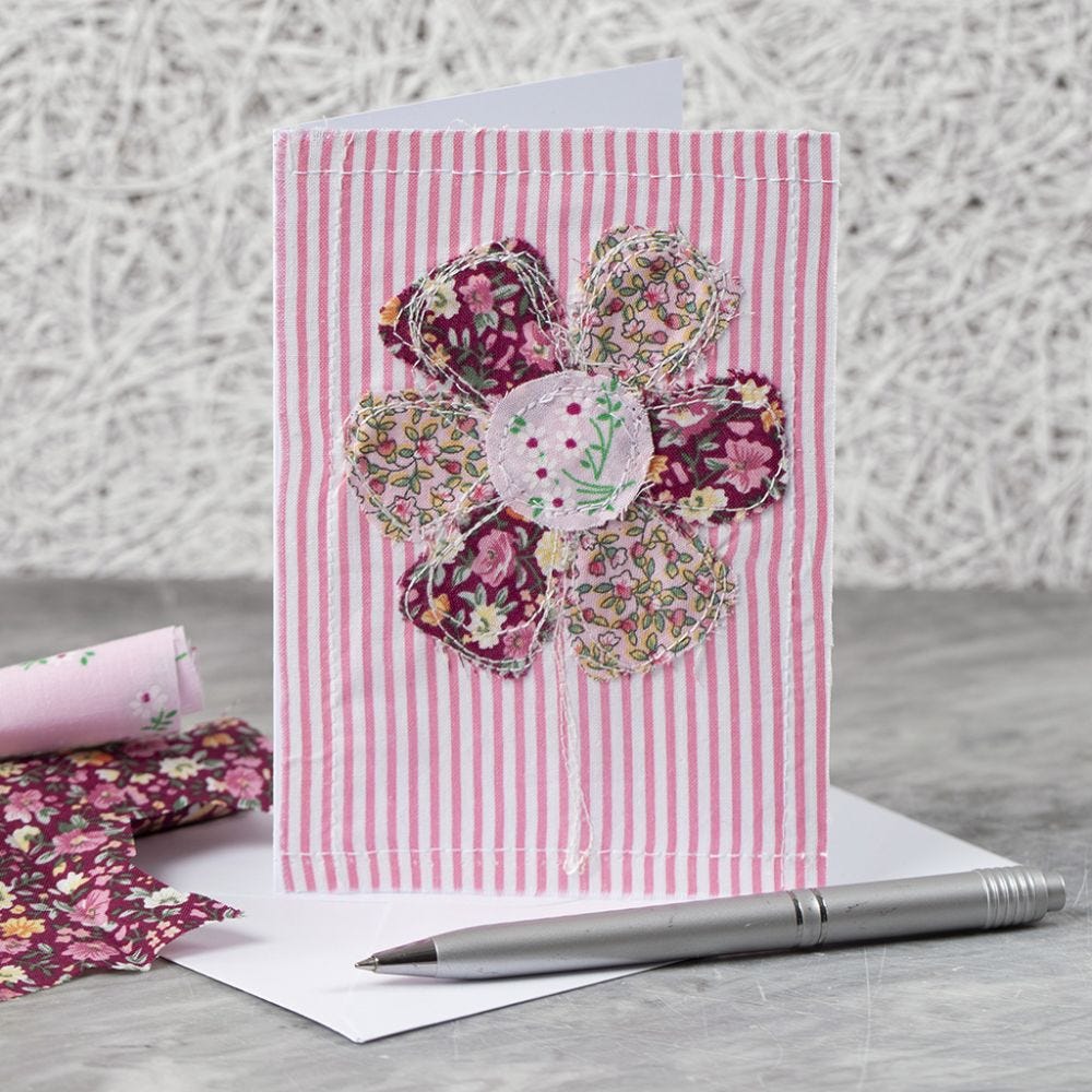 A greeting card with a sewn-on fabric flower design